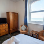 Double room with wardrobe, armchair and sea-view window at The Oasis