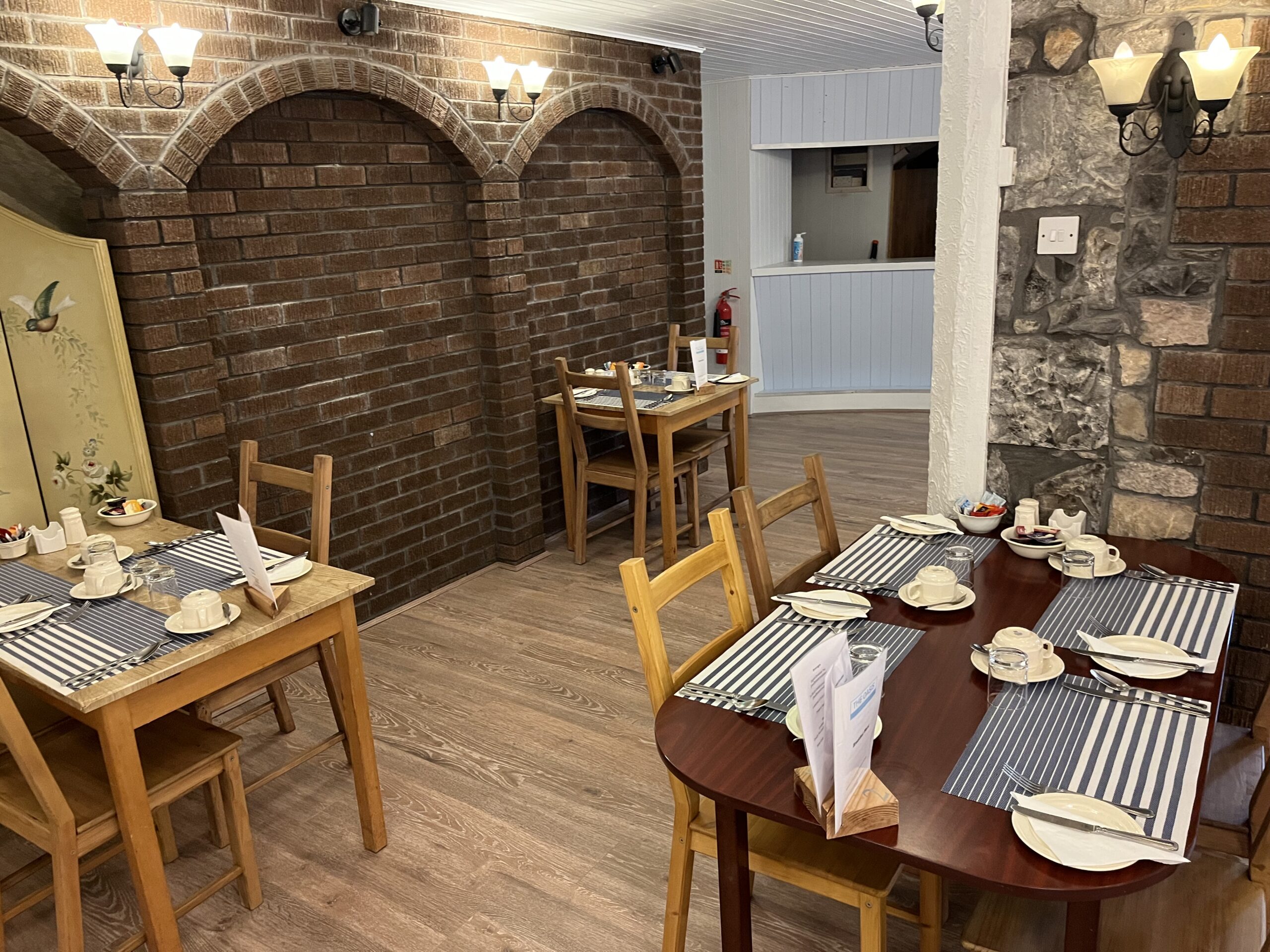 Dining room with exposed stone walls and tables set for breakfast at The Oasis