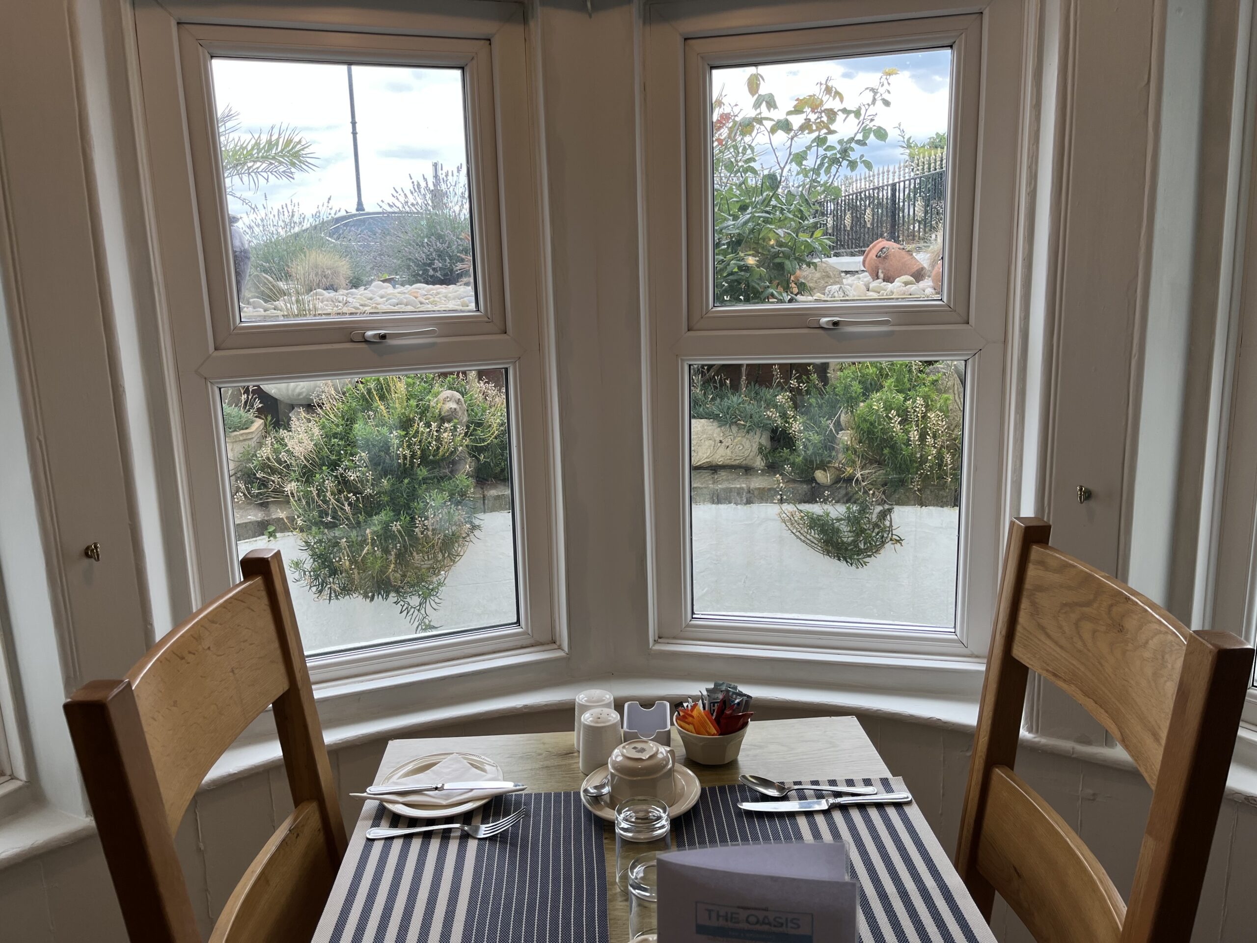Dining room bay window table set for breakfast with sea view at The Oasis
